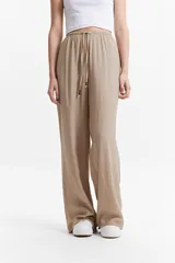 Pantalón de tiro alto color beige, con elástico y cordón regulable en la cintura.