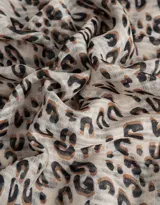 Pañuelo cuadrado de tela fina con estampado animal print en tonos beige, marrón y negro. Tiene borde con puntilla de crochet.
