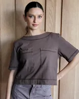 Remera negra con cuello redondo y mangas cortas, con detalle de pespuntes blancos en cuello, mangas, bolsillos frontales y ruedo.