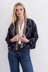 Kimono corto azul marino con estampado geométrico dorado, confeccionado en viscosa jacquard con lurex. Presenta guarda bordada en piedras y canutillos, y forrería interior.