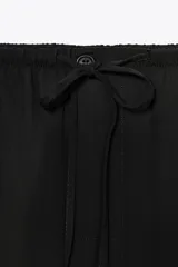 Pantalón negro de tiro medio y pierna recta, confeccionado en mezcla de viscosa y lyocell. Cuenta con cintura ajustable con cordones y bolsillos laterales ocultos en la costura.