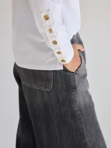 Remera blanca de algodón con escote redondo, mangas largas y pespuntes verticales a contratono.