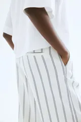 Pantalón capri de corte amplio con cintura elástica y estampado a rayas verticales azules sobre fondo blanco.