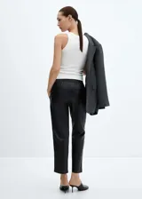 Pantalón negro de efecto piel, corte recto, tiro medio y cintura elástica con cordón ajustable.