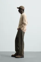 Sweater color beige con motas de colores, de tejido de punto grueso con cuello redondo y mangas largas. Presenta roturas y agujeros en el frente y las mangas.