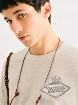 Camiseta blanca de algodón con cuello redondo y mangas cortas. Estampa rectangular con borde negro que contiene la frase "NATURAL ATMOSPHERE" en letras mayúsculas y una imagen de montañas y mar.