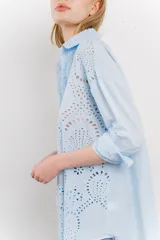 Camisa celeste de algodón con bordado calado tipo broderie, manga larga con puño angosto y botones al frente.
