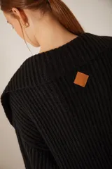 Saco largo de tejido de punto grueso color negro, con cuello shawl y bolsillos delanteros.