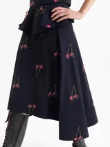 Pollera tipo plato de color negro con estampado de cerezas. Presenta un vuelo caracol irregular, siendo la espalda más larga que el delantero.