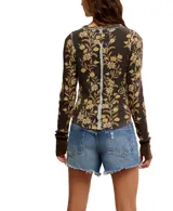 Blusa térmica color crema con estampado floral en tonos rojos y verdes, de mangas largas con puños acampanados.