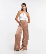 Pantalón wide leg de textura acetinada color café, con bolsillos cargo con solapa en los laterales y tira con moña en los bolsillos y en la barra. Cintura con trabillas y cierre por botón y cremallera.