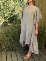 Vestido largo color beige, de corte amplio, con mangas cortas abullonadas y volado en el ruedo.