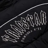 Campera puffer negra con capucha y logo Trapstar Irongate Arch Pipping v2 estampado en la espalda.