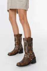 Bota marrón de estilo western, con detalles de remaches metálicos y tacón bajo.