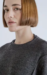 Sweater gris oscuro de corte recto, cuello redondo y mangas largas con detalle de costuras a los lados.