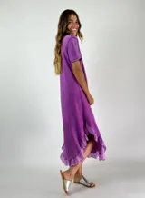 Vestido midi lila con textura arrugada, corte holgado, mangas cortas y ruedo con volados.