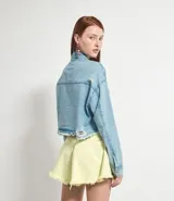 Chaqueta cropped de jean celeste, con cuello con solapa, mangas largas, bolsillos frontales, terminación gastada y cierre frontal con botones.