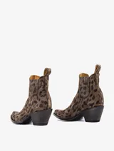 Bota corta estilo texana de cuero con estampado animal print de leopardo en tonos marrón y negro. Presenta elásticos laterales para facilitar el calce y un taco medio de madera oscura con punta fina.