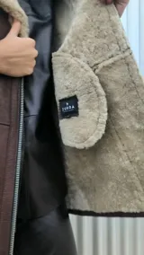 Chaqueta marrón gastado de cuero ovino con cuello y puños de piel sintética color crudo. Cierre frontal con cremallera y bolsillos laterales.