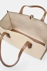 Bolso maxi shopper de hombro color beige con detalles en cuero marrón. Doble asa en contraste de tejido. Incluye bolsa de tela extraíble con cierre fruncido y tira con anilla metálica.