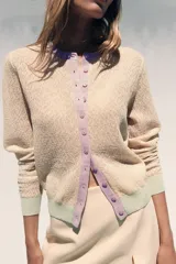 Chaqueta de punto color marrón con cuello redondo y manga larga. Presenta detalle de color azul en cuello, puños y ruedo. Cierre frontal con botones color celeste.