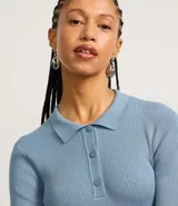 Vestido corto negro de punto con cuello polo, manga larga y botones en el escote.