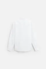 Camisa celeste de lino, de corte recto, manga larga y cuello clásico.