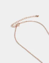 Cadena corta color oro rosa con dije de corazón, la mitad con acabado liso y la otra mitad con pequeños cristales rosados.