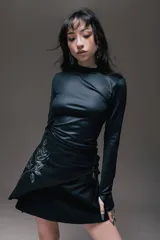 Minivestido negro con cuello alto y mangas largas. Presenta un drapeado lateral con lazos ajustables y un estampado de rosa en el frente.