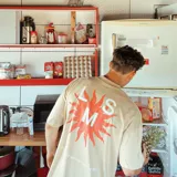 Camiseta oversize beige de algodón con estampado serigráfico bicolor en naranja y blanco en la espalda.