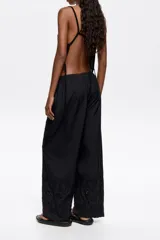 Pantalón negro de corte recto con largo tobillero, bolsillos diagonales delanteros, cintura elástica trasera y bordado inglés en el bajo de la pierna.