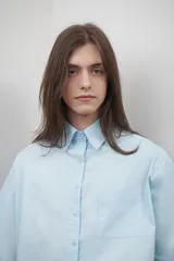 Camisa celeste de popelina de algodón, corte amplio, con cuello clásico, manga corta y bolsillo frontal. Presenta canesú con pliegue central en la espalda.