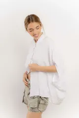 Camisa celeste de lino con corte amplio, cuello mao y mangas cortas. Presenta cierre frontal con botones y ribete negro en cuello y tapeta.