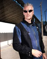 Camisa de denim negro y azul con cortes curvos y simétricos, cierre frontal de alpaca, cuello en cuero vacuno y bolsillos delanteros con bordado del logo Temblad.