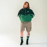 Campera deportiva unisex confeccionada en nylon liviano, color verde y negro, con calce relajado y estructura clásica. Incluye paneles diagonales en contraste y micrográfico Kaboa aplicados al frente y un gráfico en la espalda.