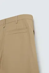 Pantalón color beige de corte ancho, con pliegues frontales dobles, bolsillos laterales y traseros de vivo. Largo cropped y cierre frontal con cremallera y botón.