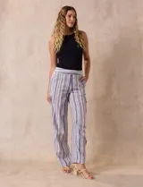 Pantalón de lino a rayas verticales en tonos beige, azul y blanco. Tiene pretina elastizada, bolsillos inclinados delanteros y bolsillo lateral tipo cargo.