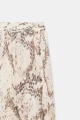 Pantalón bombacho de tiro medio con estampado de piel de serpiente en tonos beige y marrón. El bajo es abullonado y ajustable con lazada. Presenta detalle de hilo metalizado a contraste y cierre lateral con cremallera oculta.