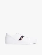 Zapatillas de corte bajo confeccionadas en piel napa color blanco. Presentan una franja lateral de tejido trenzado con los colores distintivos de la marca y una insignia metálica con el monograma TH. Cuentan con cordones al tono, suela de goma vulcanizada y logo en relieve en el talón.