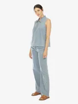 Musculosa de denim celeste, con cuello polo, escote en V con botones, sin mangas, de fit amplio y terminación desflecada.