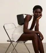 Bolso baguette negro de cuero sintético con asa larga, cierre de cremallera y apliques de spikes y detalles metálicos.