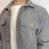 Sobrecamisa gris con diseño de espiga, cuello clásico, cierre frontal abotonado, dos bolsillos con solapa en el pecho y corte recto.