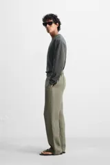 Pantalón negro regular fit confeccionado en tejido de lino. Cintura ajustable con cordón interior, bolsillos frontales y detalle de bolsillos traseros de vivo.