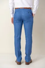 Pantalón de vestir azul marino, de corte recto, confeccionado en lino. Se ajusta a la cintura con cinturón de cuero marrón.