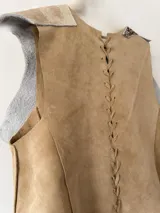 Chaleco pechera de cuero color marrón con manchas blancas, de corte irregular y diseño rústico.