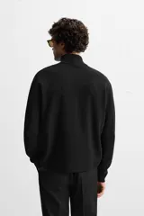 Jersey negro de punto de algodón, corte recto, cuello perkins con cremallera metálica y mangas largas terminadas en rib.