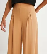 Pantalón recto color ocre, de tejido rib con textura acanalada y pliegues en la cintura.