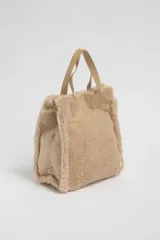 Bolso tipo tote de sherpa color beige con doble asa corta de cuero sintético.