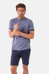 Remera de manga corta color azul grisáceo con cuello mao y tapeta de botones. Los puños de las mangas y el cuello son de color azul marino contrastante. Presenta un pequeño logo bordado en el pecho.