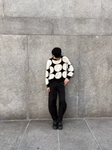 Buzo de tejido de punto color crema con grandes círculos negros estampados. Tiene cuello redondo, puños y bajo acanalados.